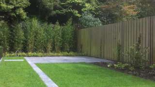 kindvriendelijke tuin met schellevis-tegels carbon 80x80x4 verhoogde taxushaag 100 cm, gaaswerk tot 250 cm, witte hortensia en lavendel. speeltoestel en schommel aan pergola. in Oisterwijk